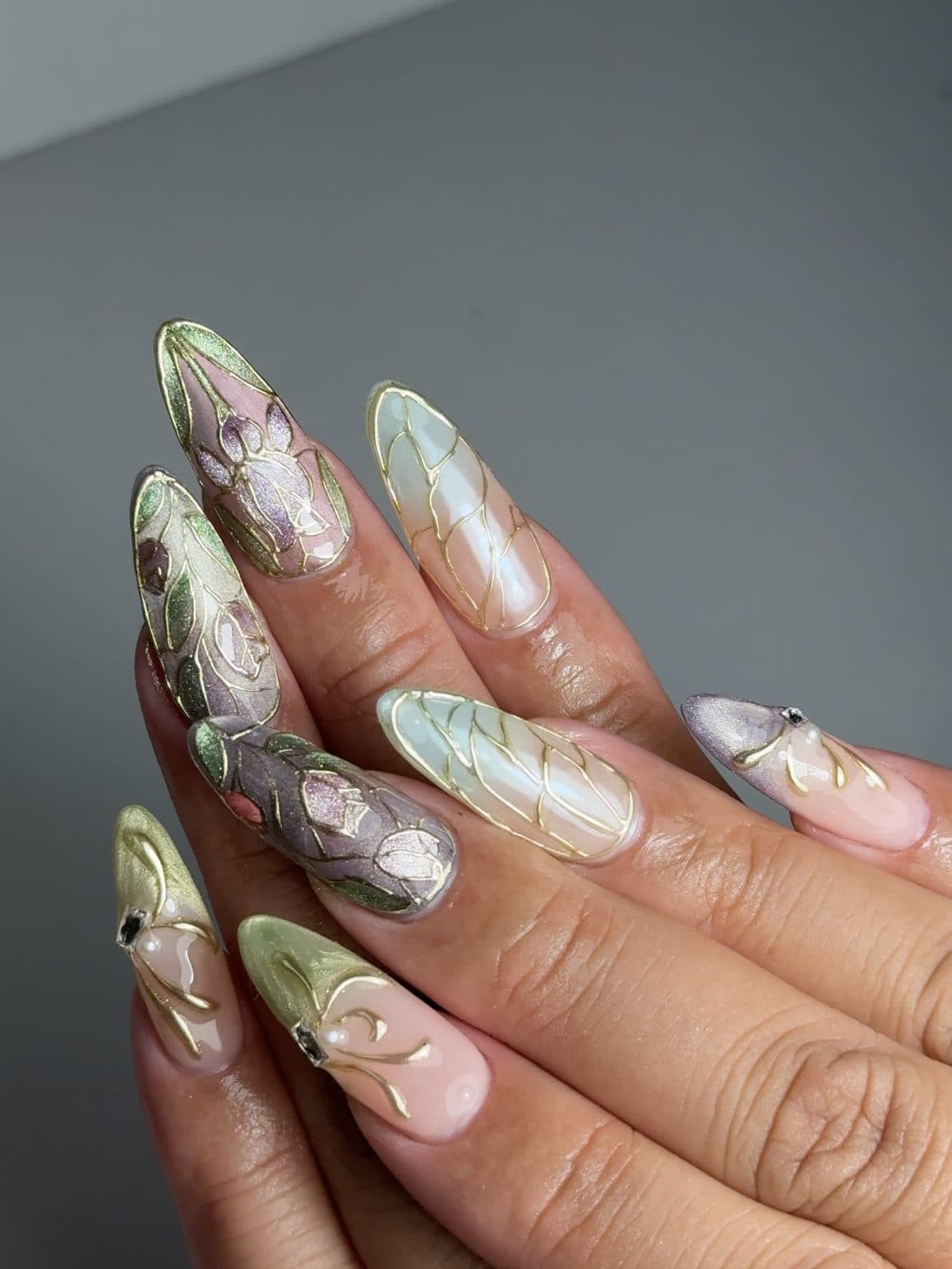 Almond Gel-X nails with sage green and lilac marble, gold wire outlines and pearl detail