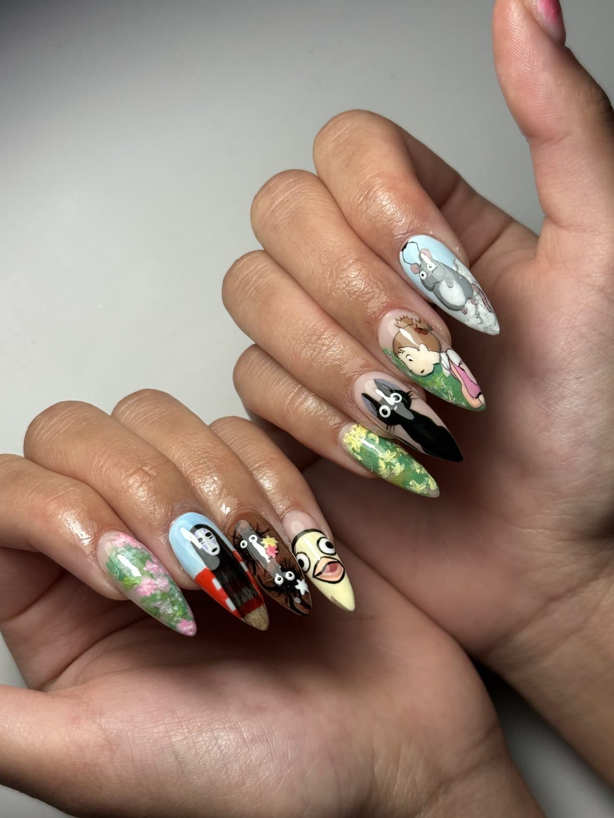 Hand-painted anime-inspired almond Gel-X set with black spirit characters and pastel scenes