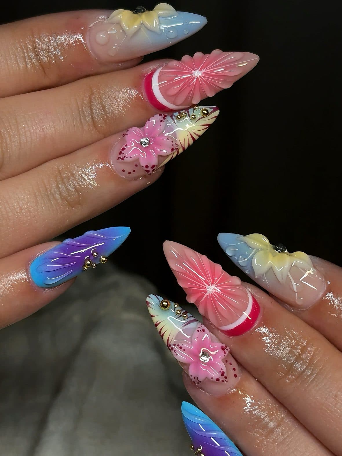 Long stiletto Gel-X set with 3D pink flowers, carved pastel petals and blue-purple ombre