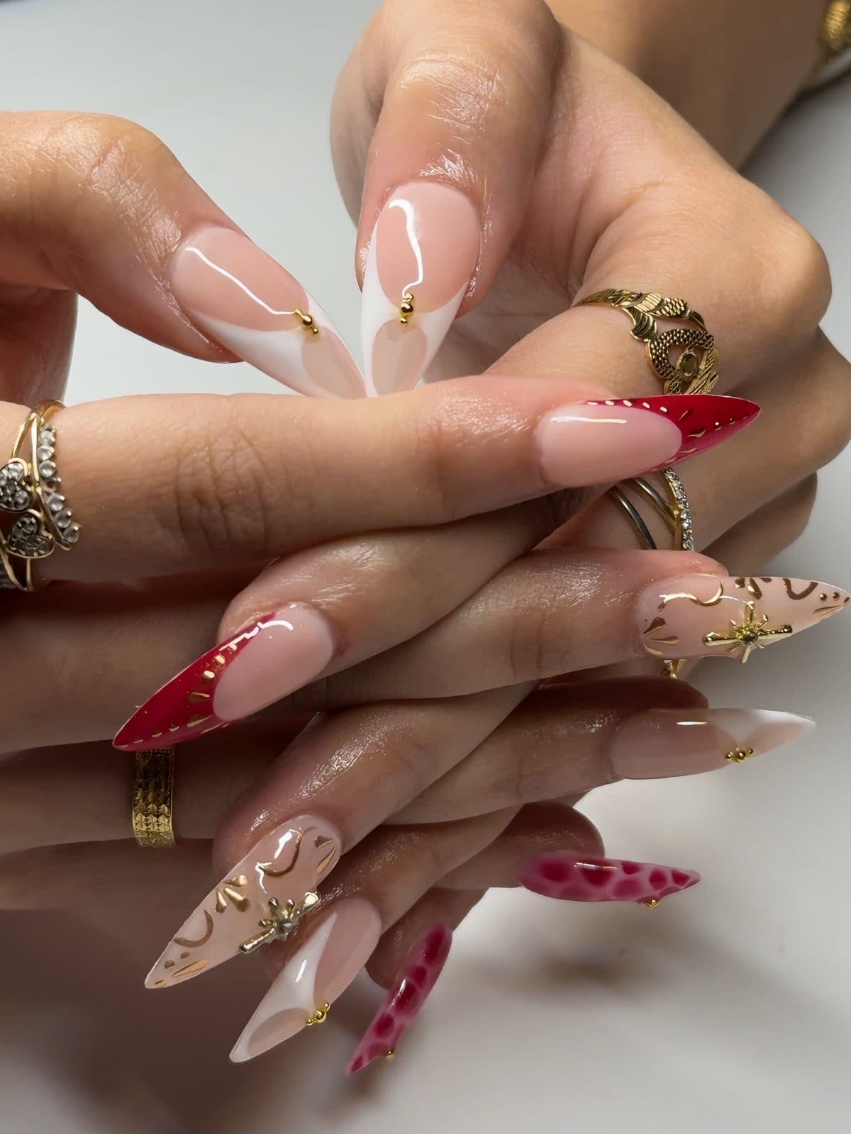 Red French tips, pink cow print and gold star charms on long almond Gel-X nails