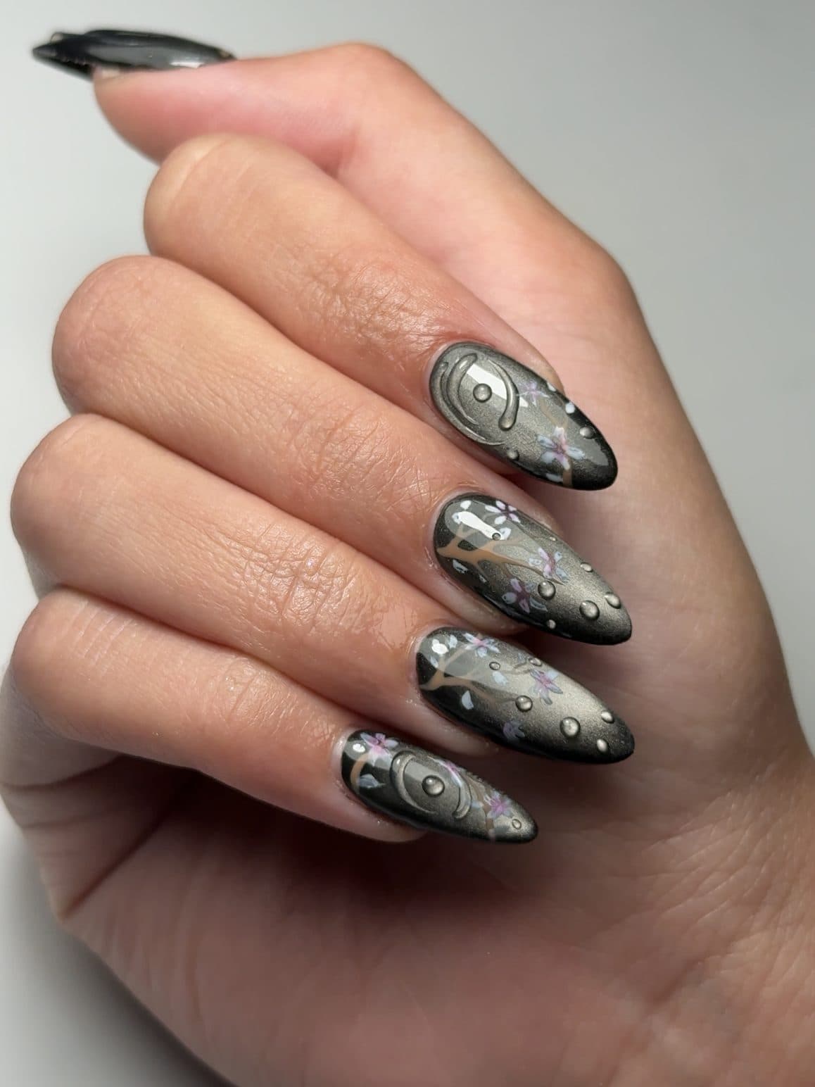 Silver chrome almond Gel-X nails with 3D raised swirls and crystal studs