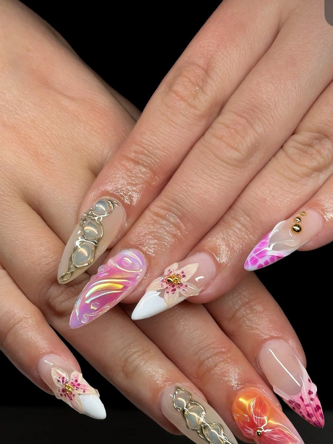 Stiletto Gel-X nails with pink starburst flowers, gold swirl charms and orange ombre
